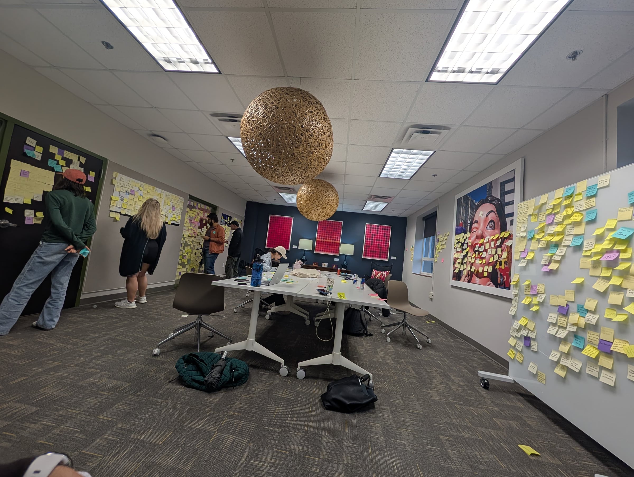 Research team members manually organizing observation notes across several walls