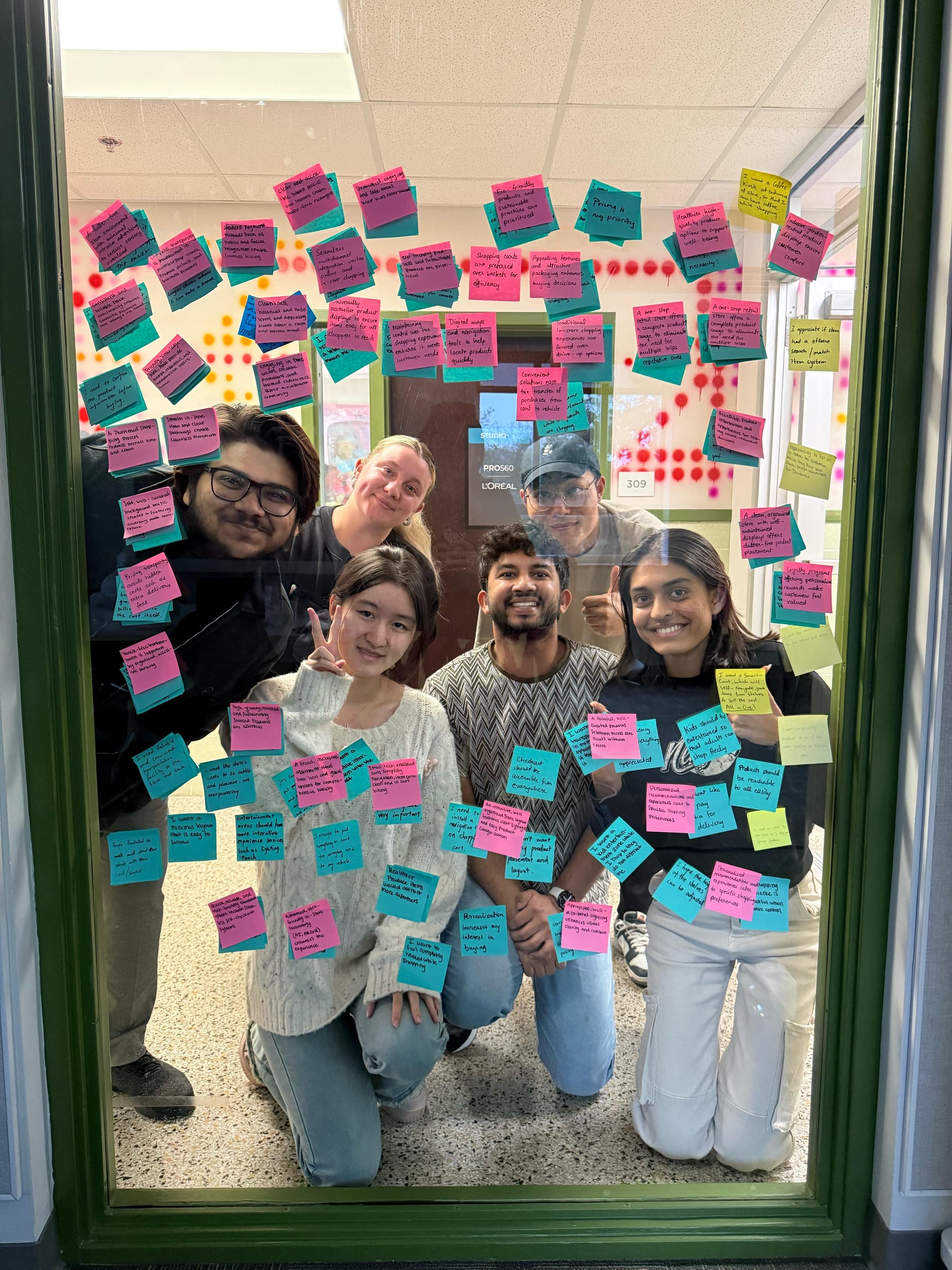 The six-person research team behind a glass surface covered with synthesized notes