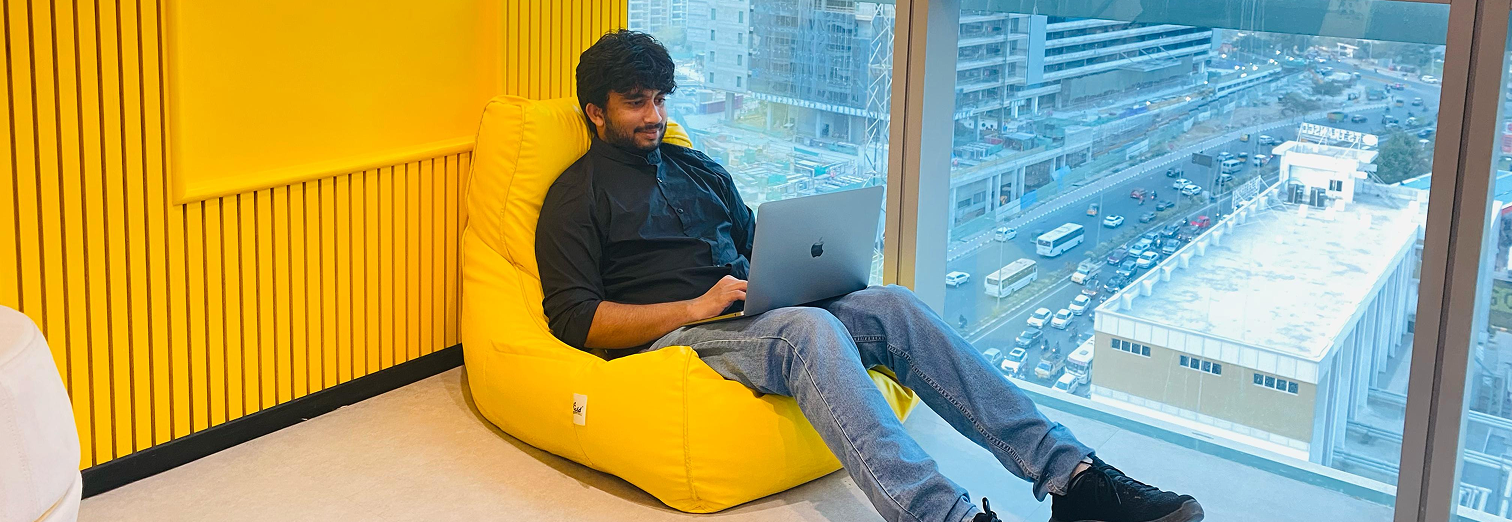 Sravan working on a laptop beside a city window