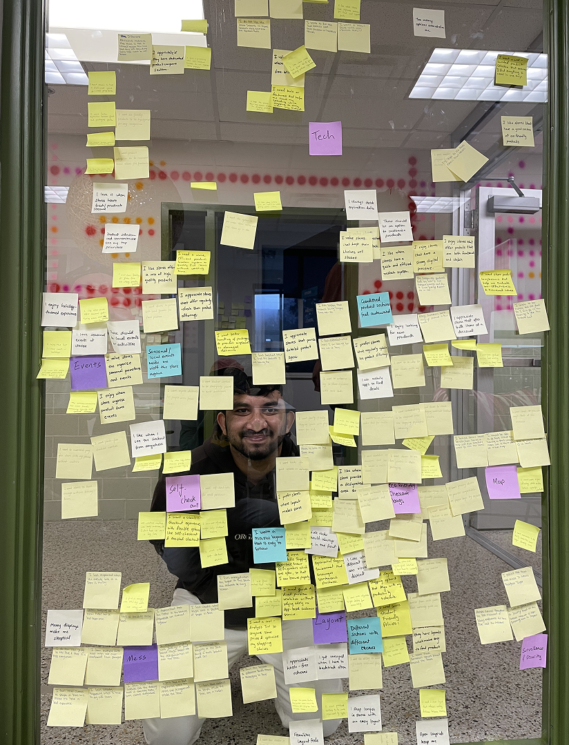Sravan behind a glass wall covered with sticky notes