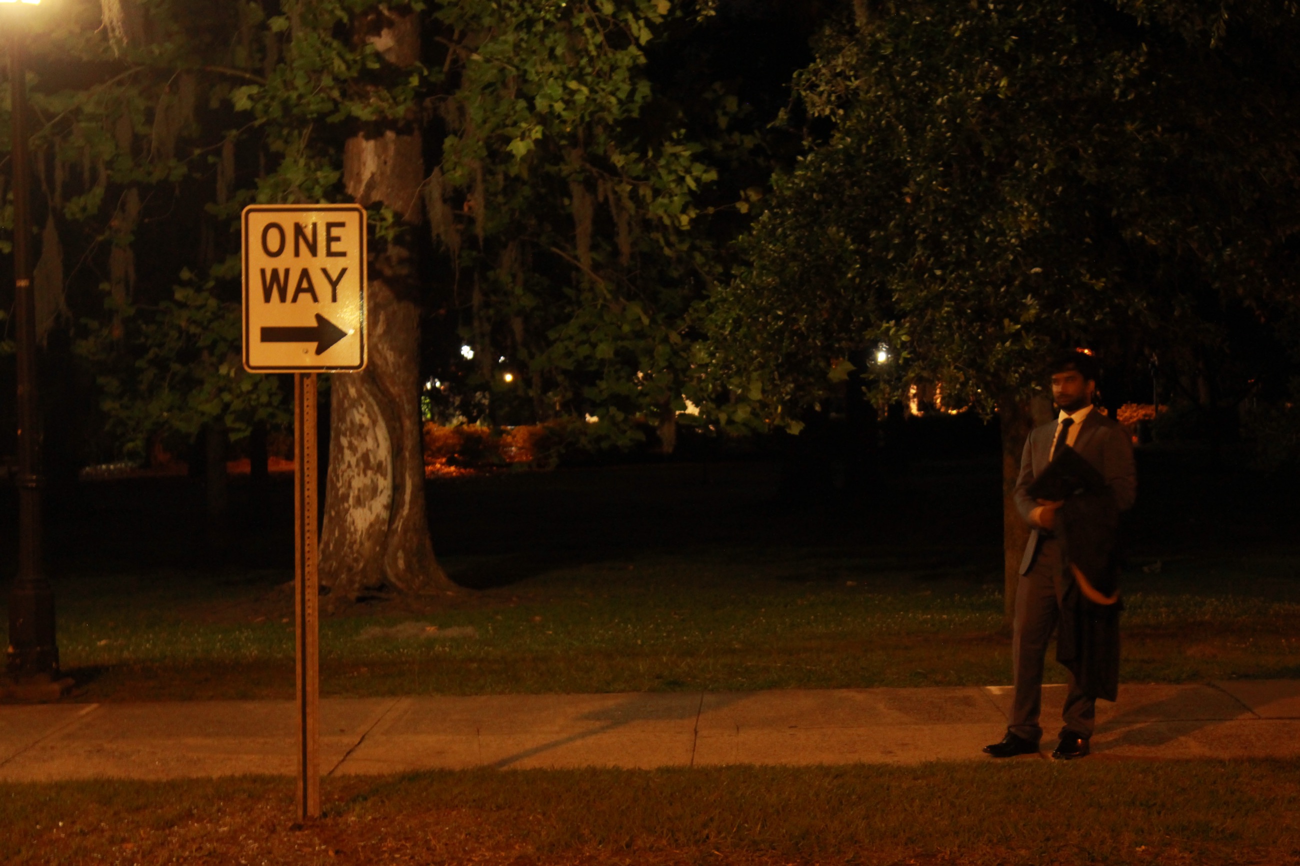 Sravan Puli standing beside a one-way sign at night